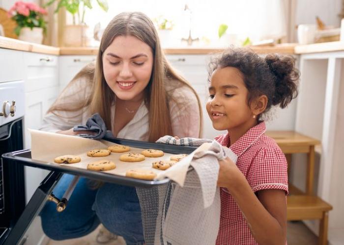 Babysitter sort des pâtisseries du four avec une fillette