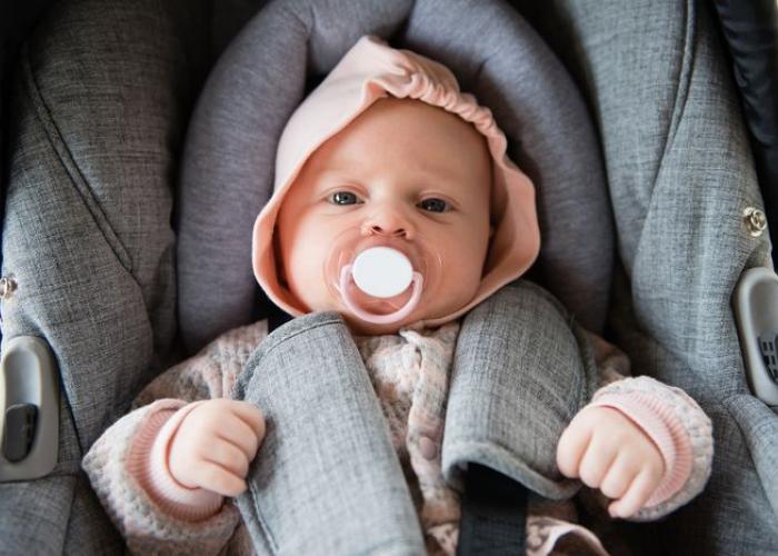 Bébé dans un siège auto avec sa tétine