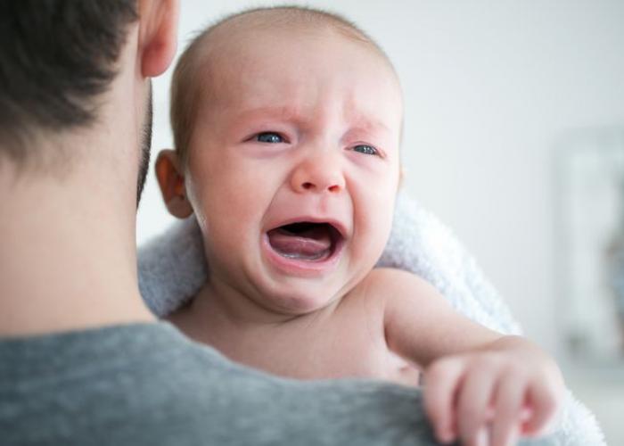 Bébé qui pleure dans les bras de son papa