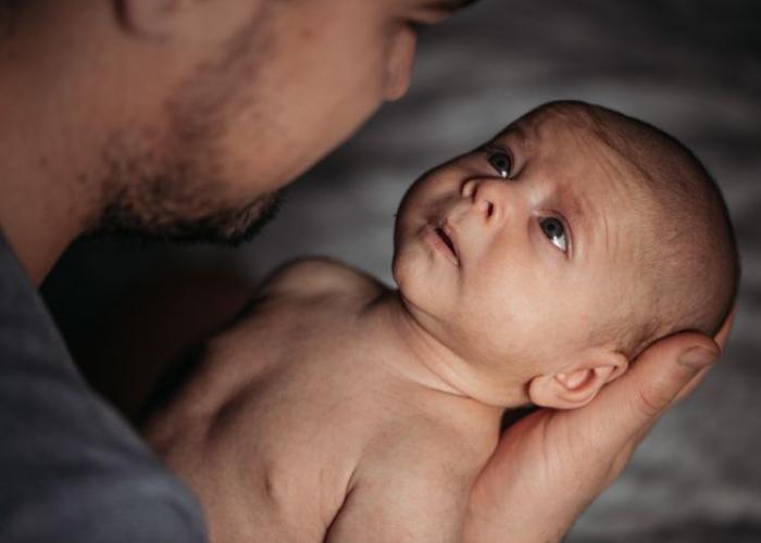 Bébé bien tenu dans les bras de son papa