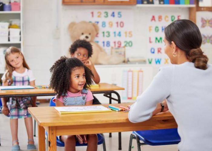Enfant dans une classe maternelle écoute la maîtresse