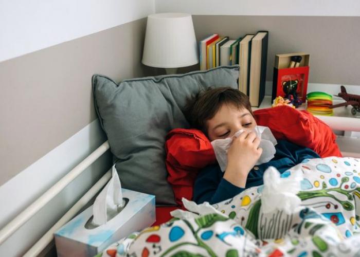 Enfant au lit avec un rhume d'hiver se mouche