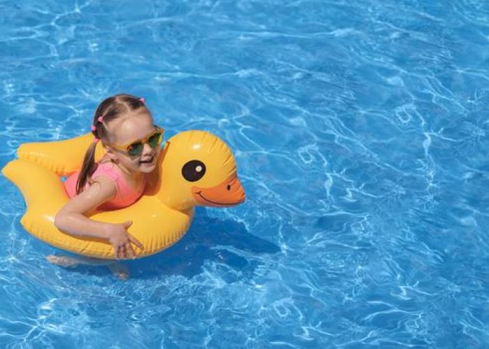 Fillette dans une piscine sur une bouée et avec des lunettes de soleil