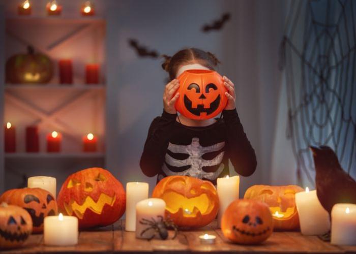 Fillette a une citrouille devant la tête pour fêter Halloween