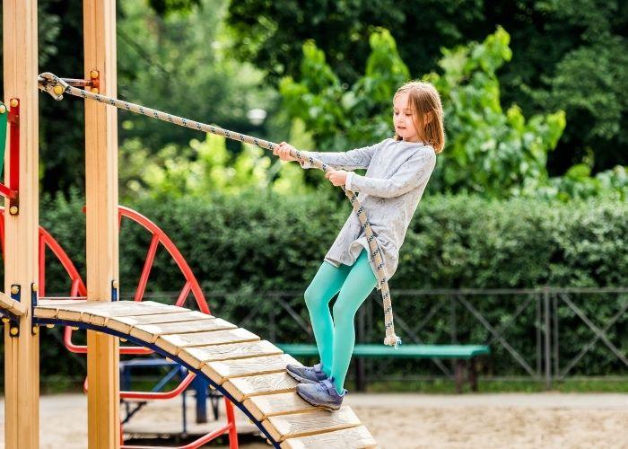 Jeune fille au parc de jeux qui s'amuse en toute sécurité Jeune fille au parc de jeux qui s'amuse en toute sécurité
