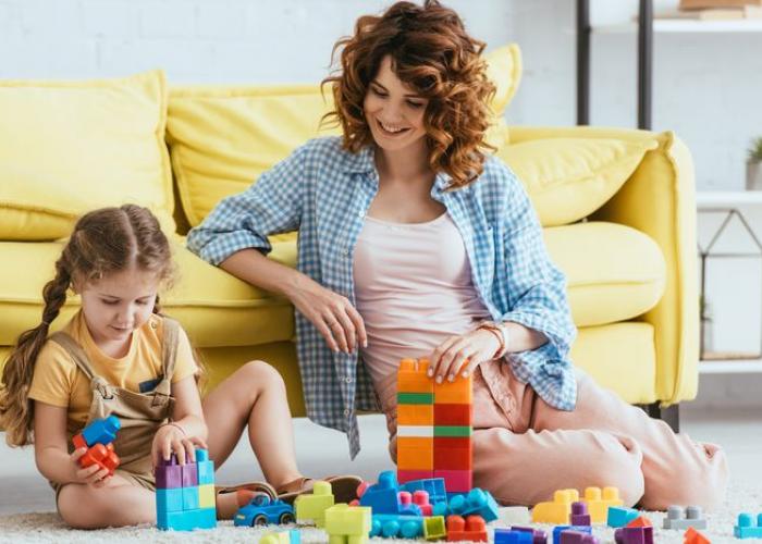 Nounou jouant avec une fillette à un jeu de construction