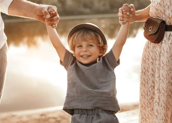 Enfant heureux tenant les mains de ses parents