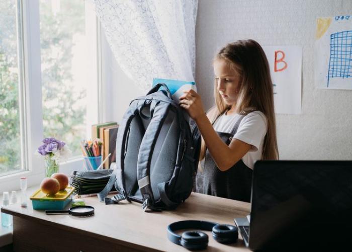 Fillette prépare son sac avant la rentrée des classes
