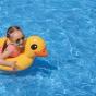 Fillette dans une piscine sur une bouée et avec des lunettes de soleil