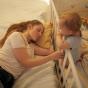 Maman dormant à côté de son bébé qui se trouve dans lit à barreau