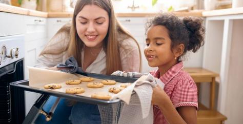 Babysitter sort des pâtisseries du four avec une fillette