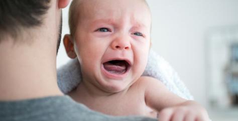 Bébé qui pleure dans les bras de son papa