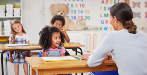 Enfant dans une classe maternelle écoute la maîtresse