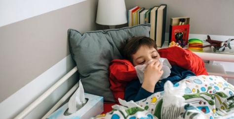 Enfant au lit avec un rhume d'hiver se mouche
