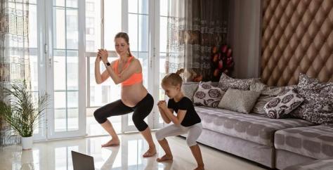 Femme enceinte fait du sport avec sa fille devant un ordinateur