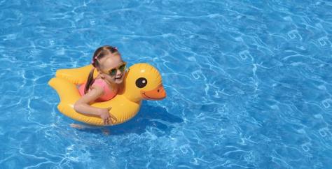 Fillette dans une piscine sur une bouée et avec des lunettes de soleil