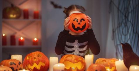 Fillette a une citrouille devant la tête pour fêter Halloween