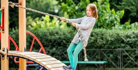 Jeune fille au parc de jeux qui s'amuse en toute sécurité